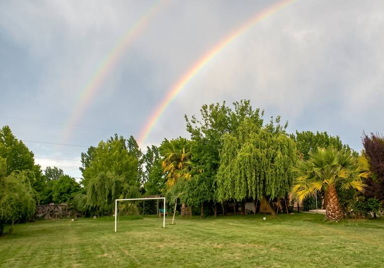 Arcoíris sobre la cancha de fútbol y el parque arbolado