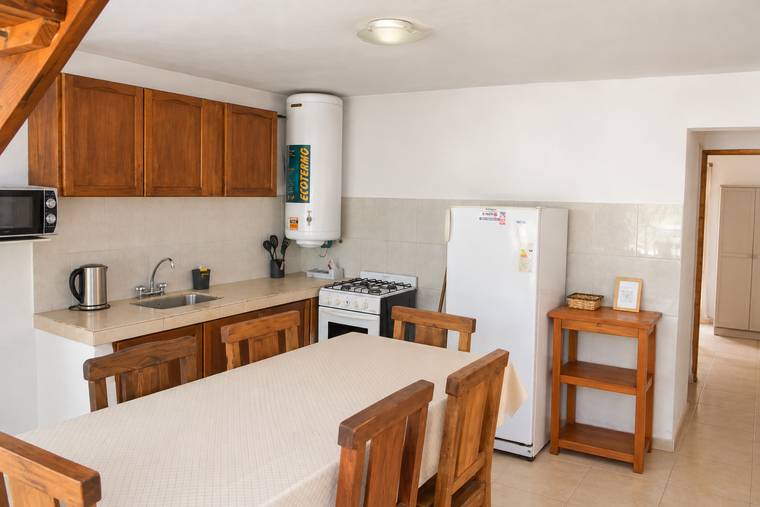 Cocina completa con anafe, horno, heladera, microondas y mesa para seis