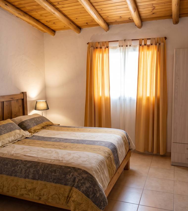 Dormitorio principal con techo de madera y cama doble