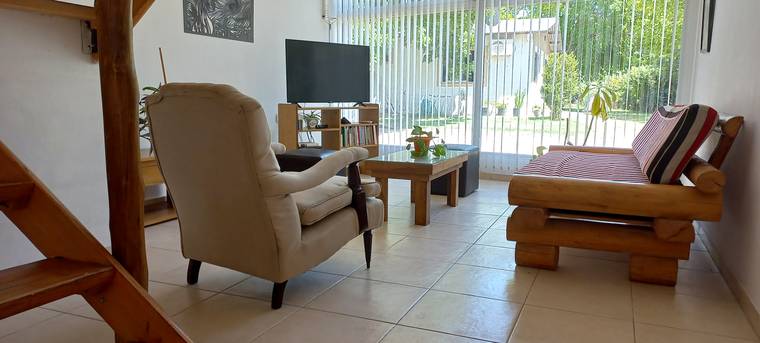 Living con sillón, biblioteca y ventanal al jardín