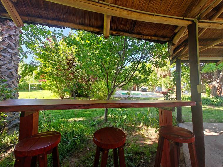 Barra de madera del quincho con vista al parque y la pileta